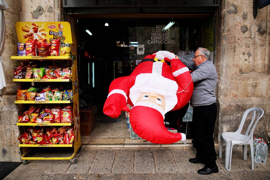 Homem segura boneco inflável de Papai Noel, em uma loja de Jerusalém - 24/12/2017 Homem segura boneco inflável de Papai Noel, em uma loja de Jerusalém - 24/12/2017