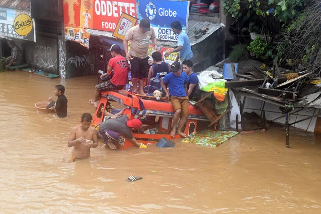 Moradores se equilibram em cima de um caminhão parcialmente coberto por água depois de tempestade atingir a cidade de Cagayan de Oro, nas Filipinas - 23/12/2017