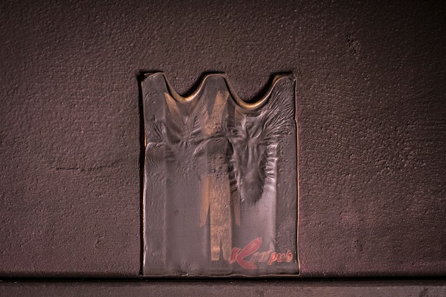 Placa do banheiro masculino ao lado do palco, parcialmente derretida pelas chamas