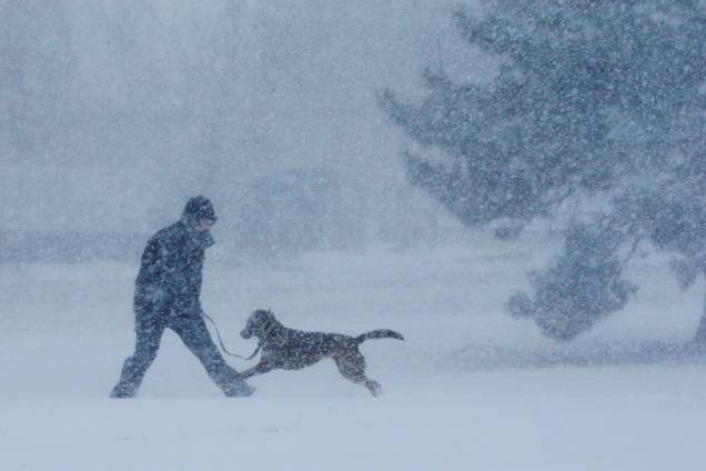 Um homem e seu cão brincam na neve durante uma tempestade de neve em Revere, no subúrbio de Boston, Massachusetts - 04/01/2018 Um homem e seu cão brincam na neve durante uma tempestade de neve em Revere, no subúrbio de Boston, Massachusetts - 04/01/2018