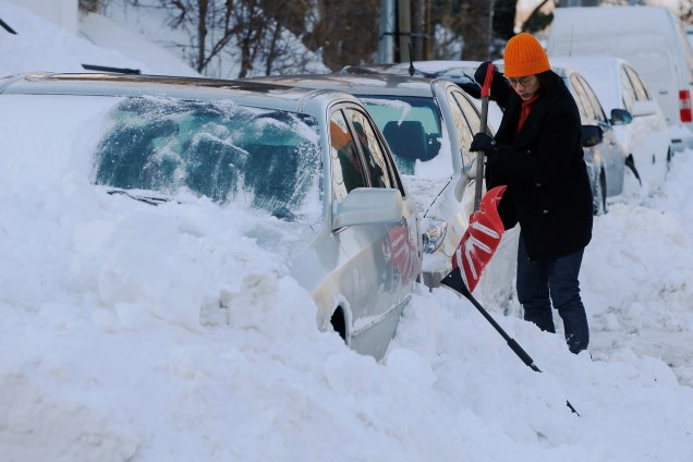 Uma mulher escava a neve acumulada em seu carro após a tempestade de neve no inverno Grayson, em Boston, Massachusetts - 05/01/2018