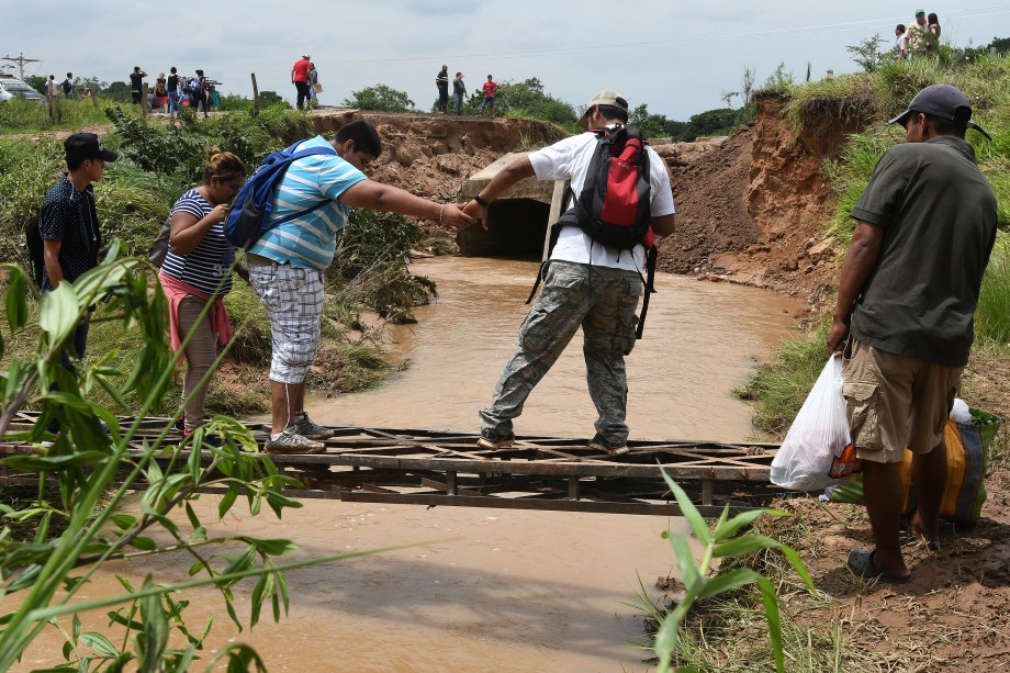 Pessoas atravessam um rio depois que fortes chuvas destruíram uma ponte perto de Porongo, em Santa Cruz, na Bolívia - 04/01/2018