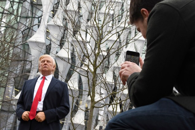 Pedestres tiram fotos de uma estátua de cera Madame Tussauds do presidente Donald Trump, do lado de fora da nova embaixada dos Estados Unidos em Embassy Gardens, no sudoeste de Londres - 12/01/2018