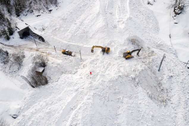 Escavadeiras removem a neve no local de uma avalanche que cobriu a ferrovia da empresa Brig Visp Zermatt Bahn entre as cidades de Visp e Taesch, nos Alpes Suíços - 10/01/2018