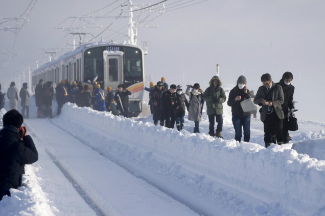 Passageiros caminham sobre os trilhos depois passarem a noite parados entre estações devido a fortes nevascas que impediram o avanço da composição, em Sanjo, na província de Niigata, Japão - 12/01/2018