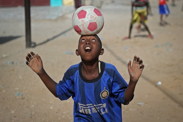Menino equilibra a bola na testa durante uma partida de futebol entre amigos na praia do Lido, em Mogadíscio, na Somália - 12/01/2018