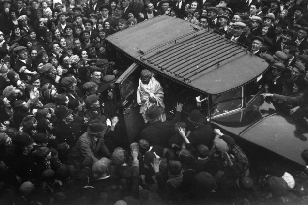 Centenas de pessoas acompanham a chegada de Gandhi a Londres para uma conferência sobre a reforma constitucional da Índia, em 1931