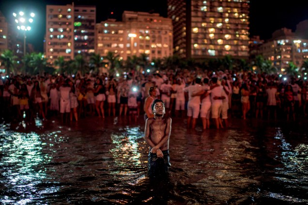 Garoto comemora a chegada do ano novo destacado da multidão, no mar da praia de Copacabana, no Rio de Janeiro - 01/01/2018