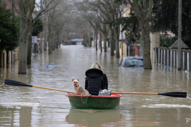 Moradora usa um barco a remo para atravessar com seu cão uma rua inundada no bairro de Villeneuve-Saint-Georges, em Paris - 24/01/2018