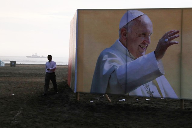 Homem caminha próximo de imagem do Papa Francisco, na praia de Huanchaco, em Trujillo - 19/01/2018