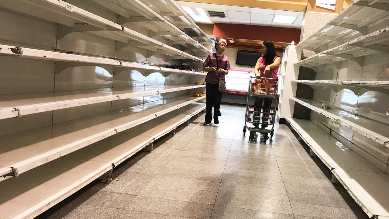 Mulheres caminham próximas de prateleiras vazias de supermercado em Caracas, na Venezuela - 09/01/2018