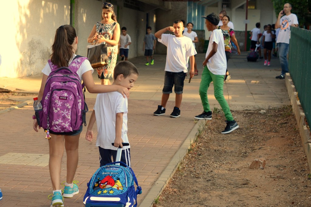 Kfar Saba, Israel - August 27, 2013: an 11-year-old girl accompanying her 6-year-old brother on the first day of school near the entrance to Remez Elementary Public School, Kfar Saba, Israel