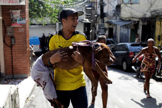 Homem carrega seu cachorro, que segundo ele foi baleado durante tiroteio entre policiais e traficantes na comunidade da Rocinha, no Rio de Janeiro - 25/01/2018