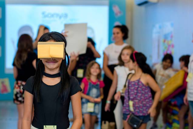 Garota brinca com óculos de realidade virtual feito com papelão e lente descartável