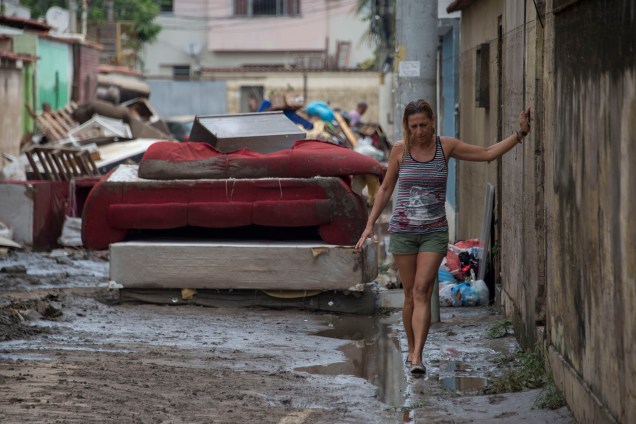 Mulher anda no meio-fio em uma rua cheia de móveis destruídos após uma inundação no bairro de Bonsucesso do Rio de Janeiro - 15/02/2018
