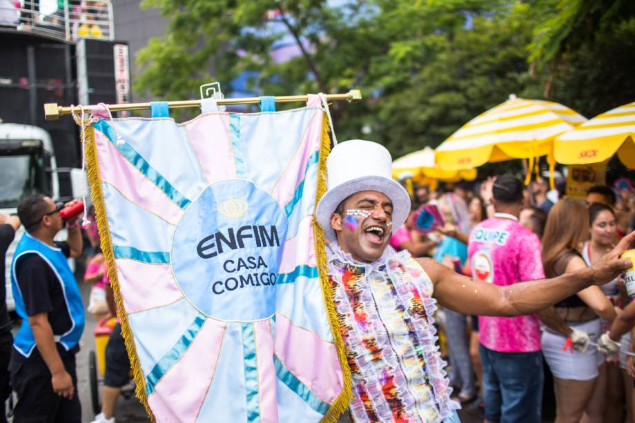 Folião segura estandarte do Bloco Casa Comigo, no pré-carnaval de São Paulo