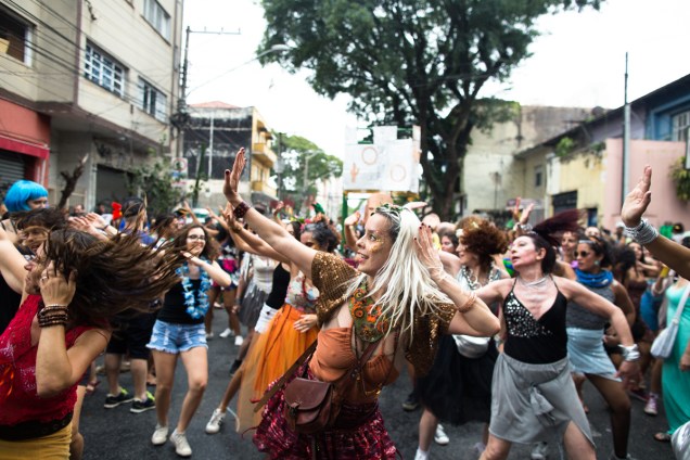 Foliãs e dançarinas do bloco esperam a concentração final do desfile para executar a derradeira dança, onde vão e vêm de um lado para o outro da rua, ao ritmo dos tambores