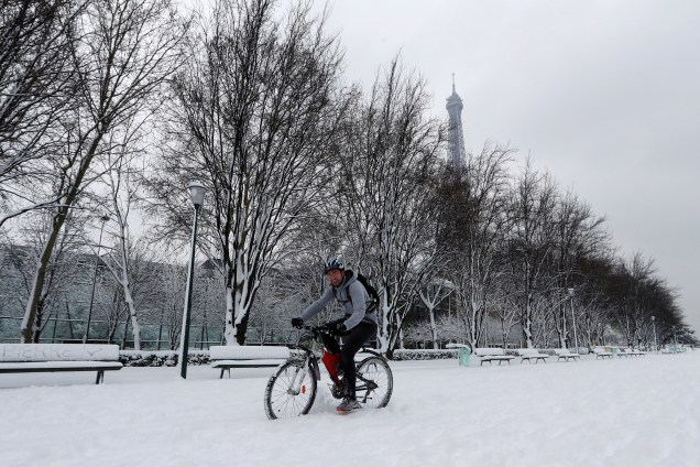 Homem monta sua bicicleta em um caminho coberto de neve, nos arredores da Torre Eiffel, em Paris - 07/02/2018