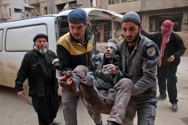 Homem é socorrido por membros da defesa civil da Síria. Os ataques aéreos do regime após três dias de intensos bombardeios no reduto rebelde de Ghouta já deixaram ao menos 300 mortos - 20/02/2018