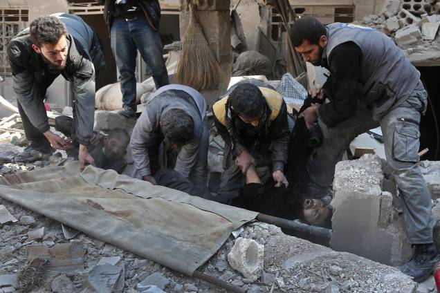 Membros da defesa civil síria resgatam um homem dos escombros após ataque aéreo das forças do governo no reduto rebelde de Hamouria, na região sitiada de Ghouta Oriental - 21/02/2018
