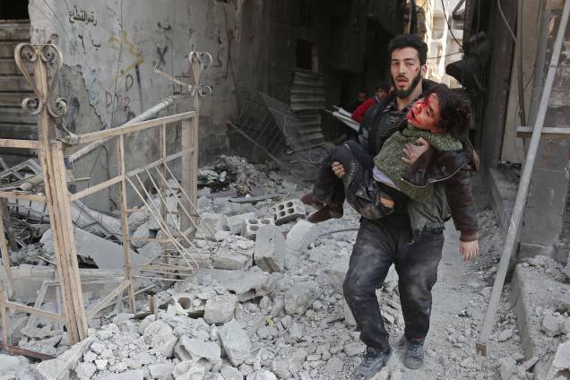 Homem resgata uma criança ferida após ataque aéreo das forças do governo sírio no reduto rebelde de Hamouria, na região sitiada de Ghouta Oriental nos arredores da capital, Damasco - 21/02/2018