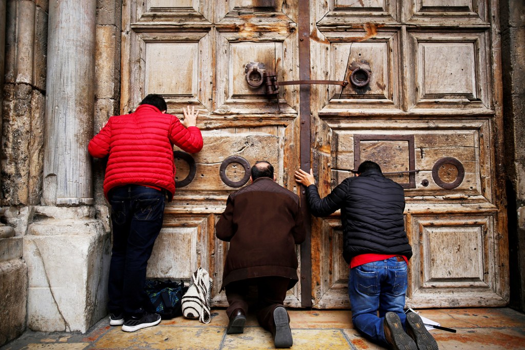 Fiéis ajoelham e rezam após o fechamento das portas da Igreja do Santo Sepulcro, em Jerusalém - 25/02/2018