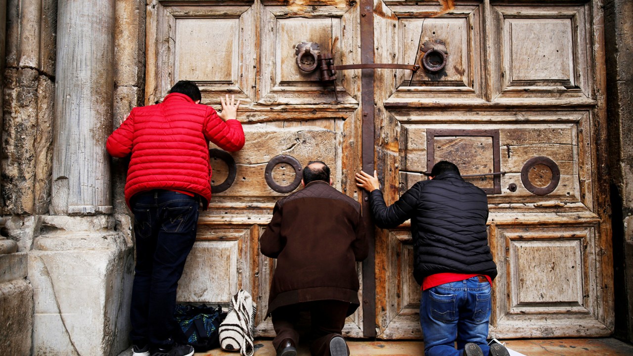 Fiéis ajoelham e rezam após o fechamento das portas da Igreja do Santo Sepulcro, em Jerusalém - 25/02/2018