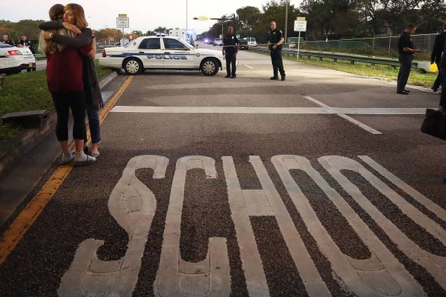Mulher abraça uma jovem em um ponto de controle da polícia perto da Escola Secundária Marjory Stoneman Douglas, na Flórida onde 17 pessoas foram mortas por um ex-aluno armado - 14/02/2018