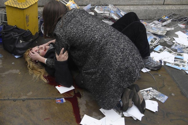 Mulher é vista ajudando uma vítima ferida no chão depois que Khalid Masood dirigiu seu carro na direção de pedestres matando quatro, além de um policial na Westminster Bridge em Londres, Grã-Bretanha - 22/03/2017