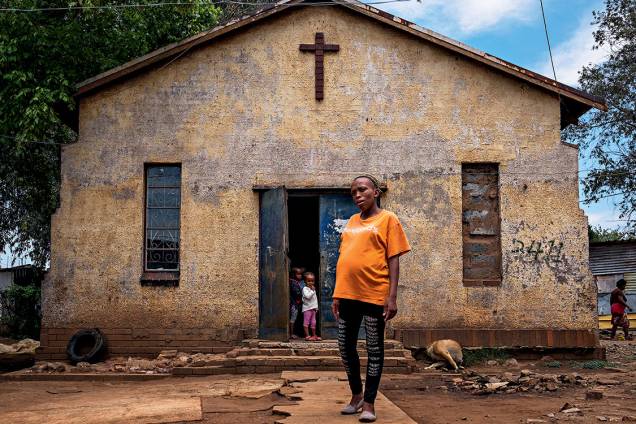 À espera do voo alto - Mãe de uma menina de 6 anos, a professora Fisokuhle Mdzebu, de 29 anos, exibe o barrigão de nove meses do segundo filho, em frente à igreja onde funciona a creche em que trabalha: “Meus pais não pisaram na escola, eu parei antes da faculdade, mas meus filhos certamente terão muito mais chances”, diz À espera do voo alto - Mãe de uma menina de 6 anos, a professora Fisokuhle Mdzebu, de 29 anos, exibe o barrigão de nove meses do segundo filho, em frente à igreja onde funciona a creche em que trabalha: “Meus pais não pisaram na escola, eu parei antes da faculdade, mas meus filhos certamente terão muito mais chances”, diz