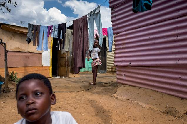 CONTRASTE - Em meio às cenas de pujança, brotam em Soweto pequenas favelas como esta, onde moram as irmãs Siphokazi, de 4 anos (à frente), e Soyama, 6 anos (no fundo), junto com a mãe e a avó: na esteira do desemprego, muita gente que subiu experimenta agora queda na renda. Soyama, com jeito meio adulto, acredita: “Sei que a situação vai melhorar” CONTRASTE - Em meio às cenas de pujança, brotam em Soweto pequenas favelas como esta, onde moram as irmãs Siphokazi, de 4 anos (à frente), e Soyama, 6 anos (no fundo), junto com a mãe e a avó: na esteira do desemprego, muita gente que subiu experimenta agora queda na renda. Soyama, com jeito meio adulto, acredita: “Sei que a situação vai melhorar”