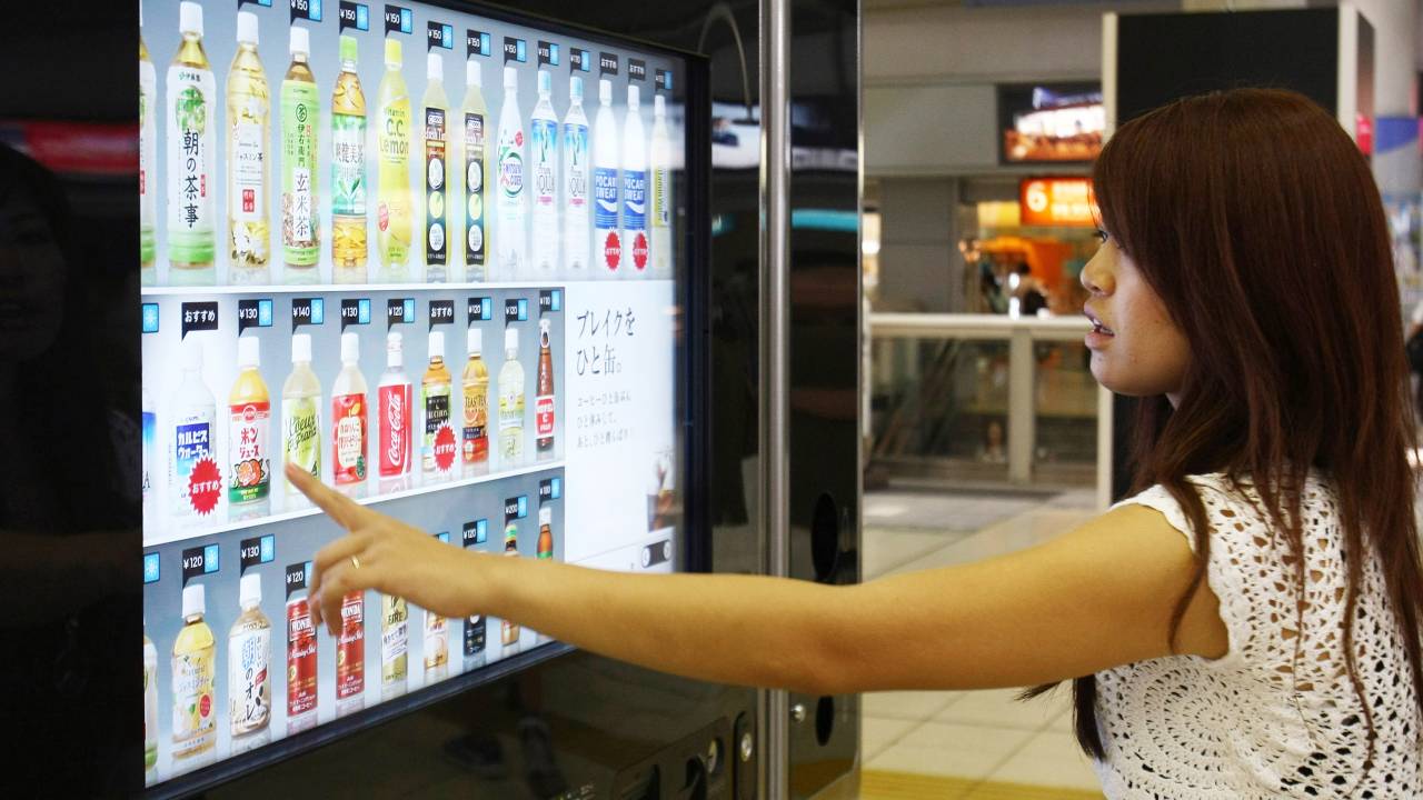 Mulher escolhe bebida em máquina na estação de trem Shinagawa, em Tóquio, no Japão