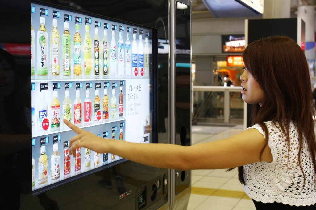 Mulher escolhe bebida em máquina na estação de trem Shinagawa, em Tóquio, no Japão