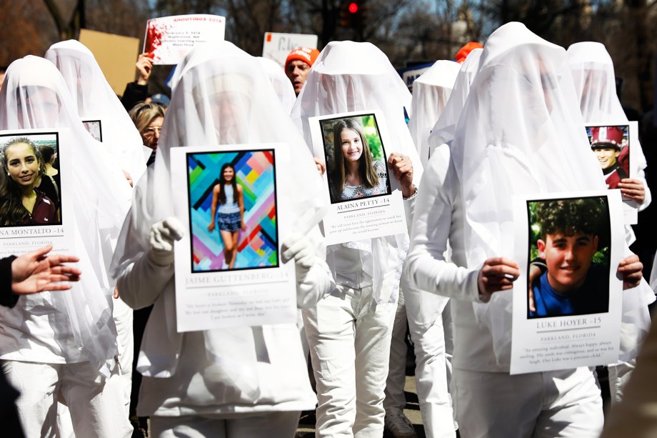 Manifestantes seguram fotos de vítimas de massacres em escolas americanas, durante protesto contra armas de fogo, denominado 'March for Our Lives', em Nova York - 24/03/2018
