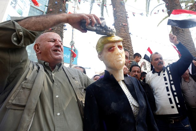 Um palestino coloca um sapato em um manequim representando o presidente dos EUA, Donald Trump, durante um protesto contra os ataques aéreos liderados pelos EUA em Damasco, em Nablus, na Cisjordânia ocupada - 14/04/2018