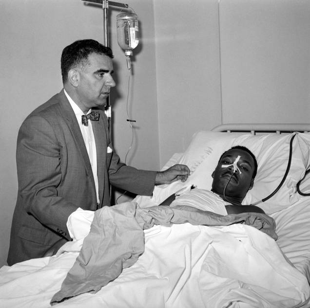 Após uma ciriurgia de 3 horas para remover uma faca do peito de Martin Luther King Jr., o Dr. Emil A. Naclerio fica ao seu lado no leito do hospital Harlem - 20/09/1958