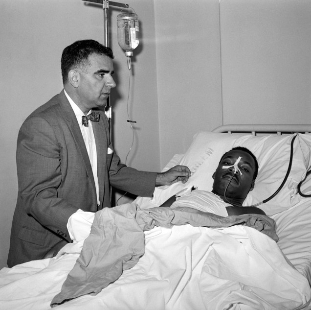 Após uma ciriurgia de 3 horas para remover uma faca do peito de Martin Luther King Jr., o Dr. Emil A. Naclerio fica ao seu lado no leito do hospital Harlem - 20/09/1958