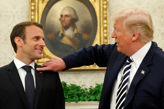 O presidente dos Estados Unidos, Donald Trump, limpa o paletó do presidente francês Emmanuel Macron após coletiva de imprensa na Casa Branca, em Washington - 24/04/2018