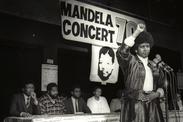 Winnie Mandela levanta a mão em uma saudação ao poder negro após anunciar que um enorme show pop será realizado para marcar o 70º aniversário de seu marido, o líder nacionalista negro encarcerado Nelson Mandela - 17/07/1988