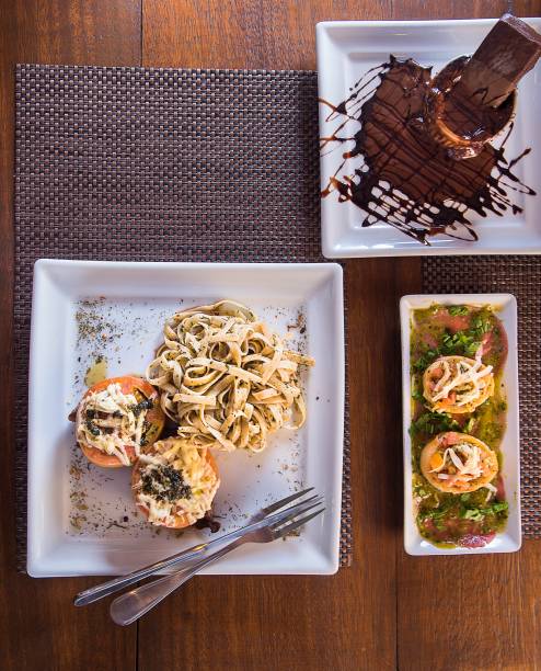 Menu completo O Tal do Bistrô em três refeições: entrada: mini espeto de pernil, principal: filé de capresi com fettuccine ao pesto, sobremesa: gateau de chocolate