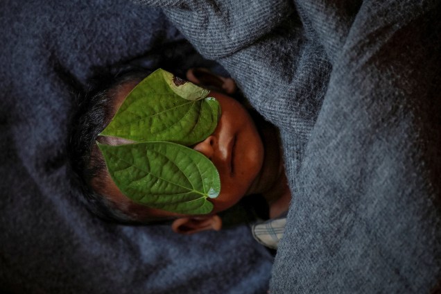 Folhas de bétele cobrem o rosto do refugiado Rohingya de 11 meses de idade, Abdul Aziz, cujo corpo embrulhado jazia em seu abrigo familiar depois que ele morreu lutando contra febre alta e tosse severa no campo de refugiados de Balukhali, perto de Cox's Bazar, no Bangladesh - 04/12/2017