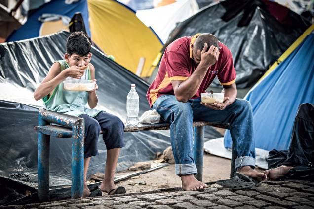 Ironia - Pai e filho almoçam na Praça Simón Bolívar, em Boa Vista: abrigo improvisado Ironia - Pai e filho almoçam na Praça Simón Bolívar, em Boa Vista: abrigo improvisado