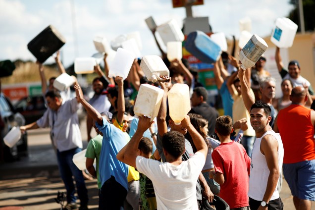 Pessoas são vistas carregando galões vazios próximas de posto de combustíveis em Brasília (DF) - 25/05/2018