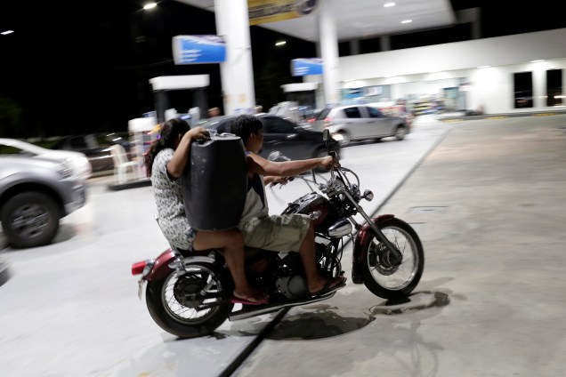 Mulher deixa um posto de combustível carregando galão de gasolina sobre uma moto em Manaus (AM) - 25/05/2018