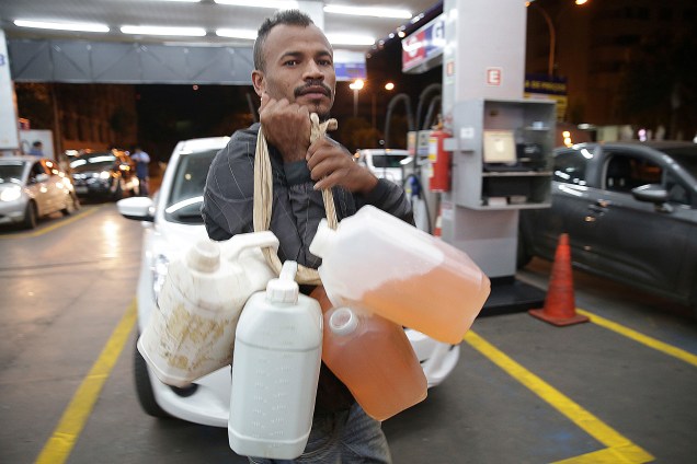 Homem carrega galões com gasolina em posto de combustível em Brasília - 26/05/2018
