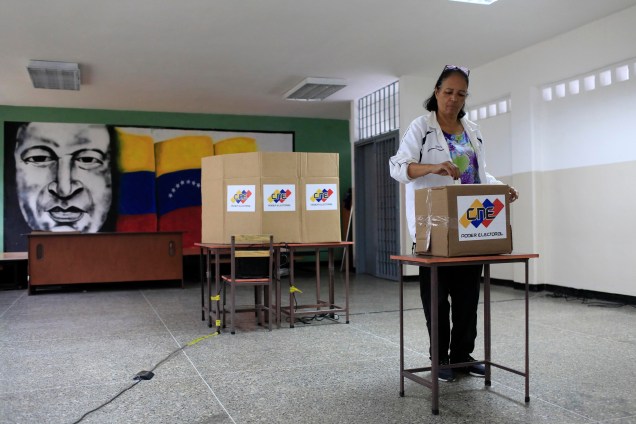 Com uma imagem do falecido presidente venezuelano, Hugo Chávez ao fundo, cidadã venezuelana vota durante a eleição presidencial em Caracas - 20/05/2018