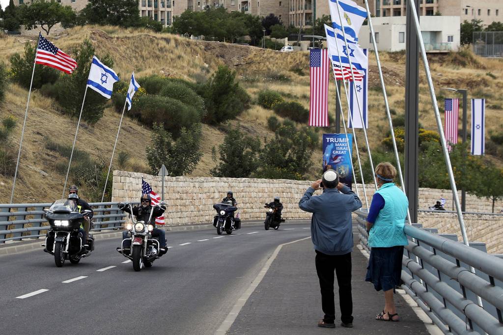 Pedestres observam passagem de motociclistas nas ruas de Jerusalém com bandeiras, antes da Inauguração da embaixada americana - 13/05/2018