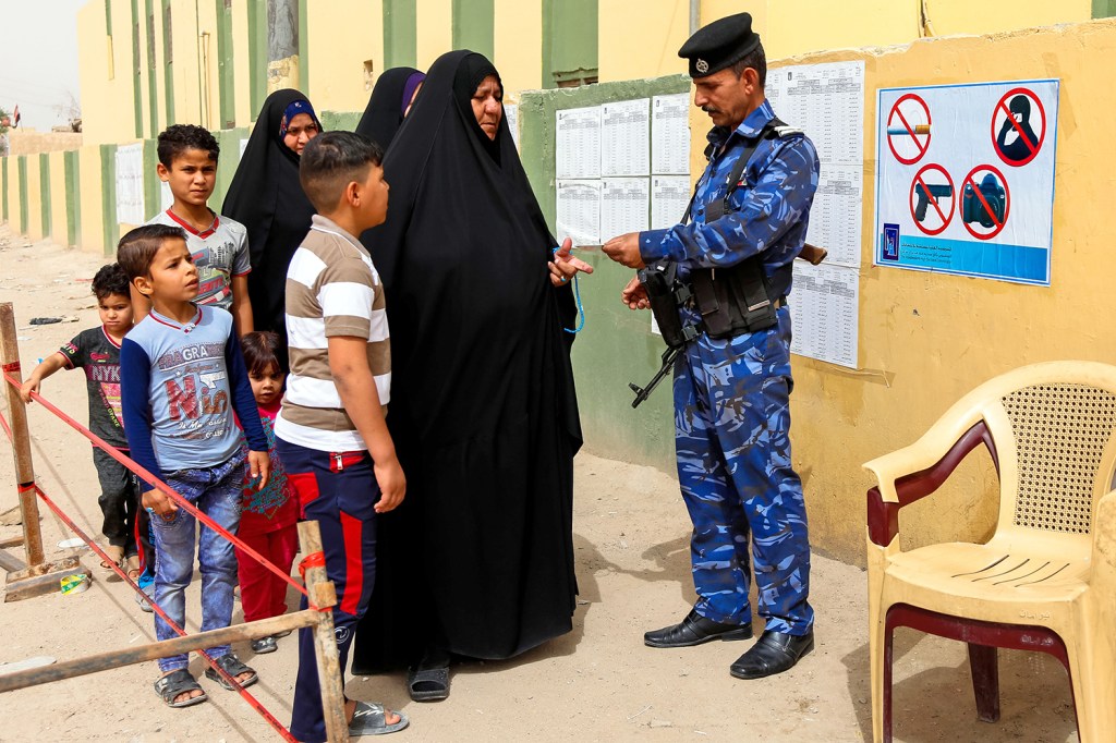 Mulher apresenta cartão de identidade para segurança em local de votação, na cidade de An-Najaf, no Iraque - 12/05/2018