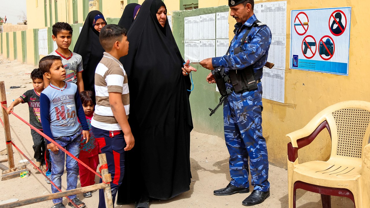 Mulher apresenta cartão de identidade para segurança em local de votação, na cidade de An-Najaf, no Iraque - 12/05/2018