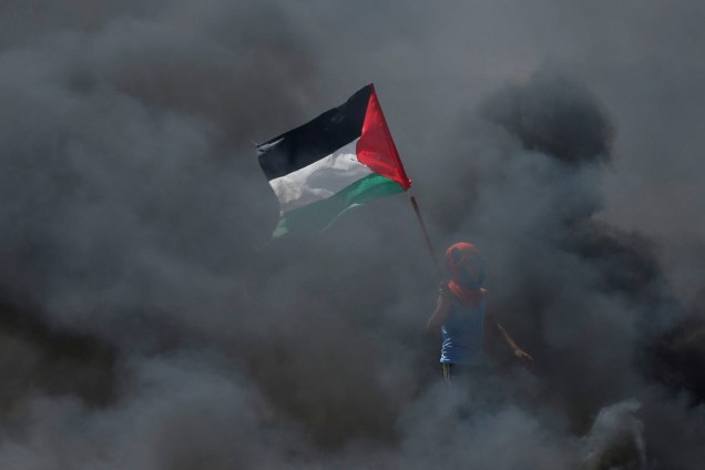 Manifestante segura uma bandeira palestina em meio a fumaça durante protesto contra a mudança da embaixada americana para Jerusalém - 14/05/2018